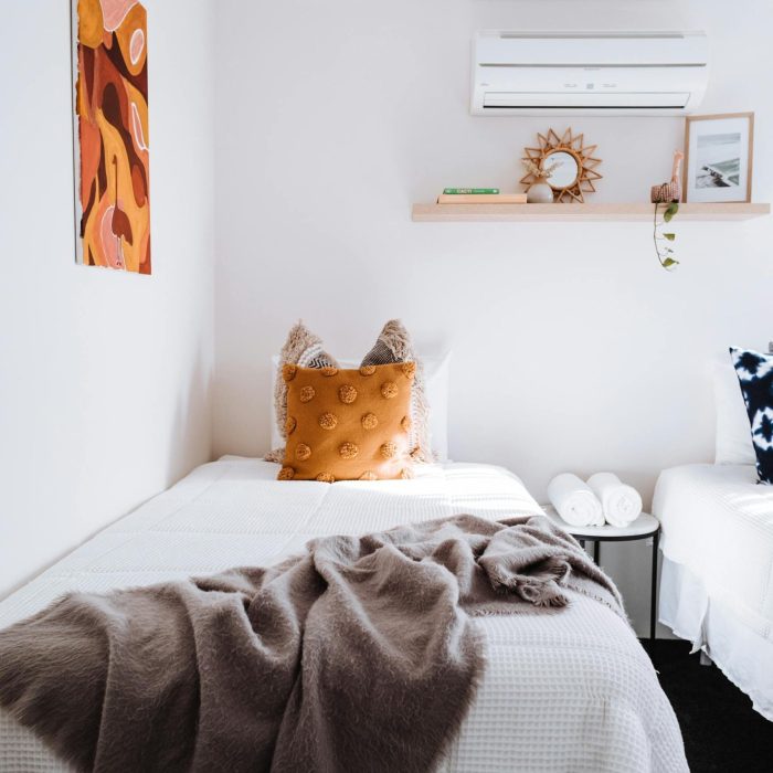 A minimalist bedroom featuring a single bed with soft textures, warm decor, and modern design.